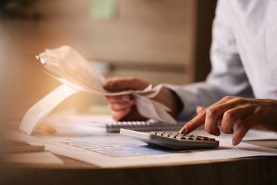 Closeup-of-economist-using-calculator-while-going-through-bills-and-taxes-in-the-office